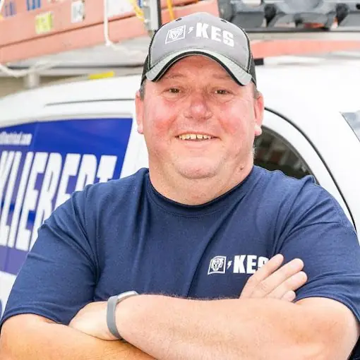 Fred Kliebert, owner of Kliebert Electrical Services, leaning against a branded service van